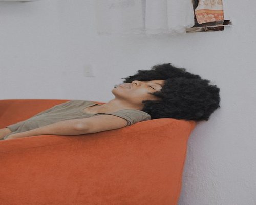 A person taking a break, closing their eyes and relaxing on a couch